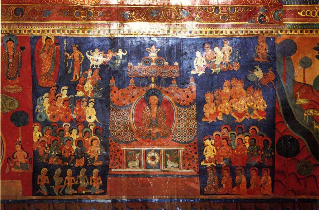 Tibet Guge 07 Tsaparang Red Temple 10 Band Life of Buddha  nowhere has it (the life of Buddha) been represented with so many details, with such a richness of scenes and with such a movement as here at Tsaparang. These frescoes have to be singled out as works of art.  Still above, the Buddha standing with the pindapatra in his right hand, indicates his resolution to deliver the famous first sermon. He starts walking towards Sarnath and en route meets the ajivaka Upagana, here represented with the ascetic stick: it is to him that he reveals his proposal to go to Banares to preach the law. The scene of preaching is, in fact, represented on the following panel. The Buddha sits on a throne covered by a rich canopy, with his hands in the attitude of the preaching mudra. On the basement of the throne are the traditional symbols of this culminating moment in the life of the Saint of the Sakyas namely, in the middle, the wheel representing, according to ancient symbolism, the first preaching; and on both sides two deer, reminding of the park actually called the Deer Park, where the famous ceremony was pronounced. Around him, in the act of devoted concentration and kneeling as a mark of homage, is a numerous crowd of every kind of creature: garuda above, nagas slightly below, gandharva and kinnaras, and then deities guided by Brahma and ascetics. The five emaciated yogins praying in the foreground possibly reproduce his first disciples. - Giuseppe Tucci: The Temples of Western Tibet and their Artistic Symbolism (1935). Photo - Weyer/Aschoff: Tsaparang, Tibets Grosses Geheimnis.